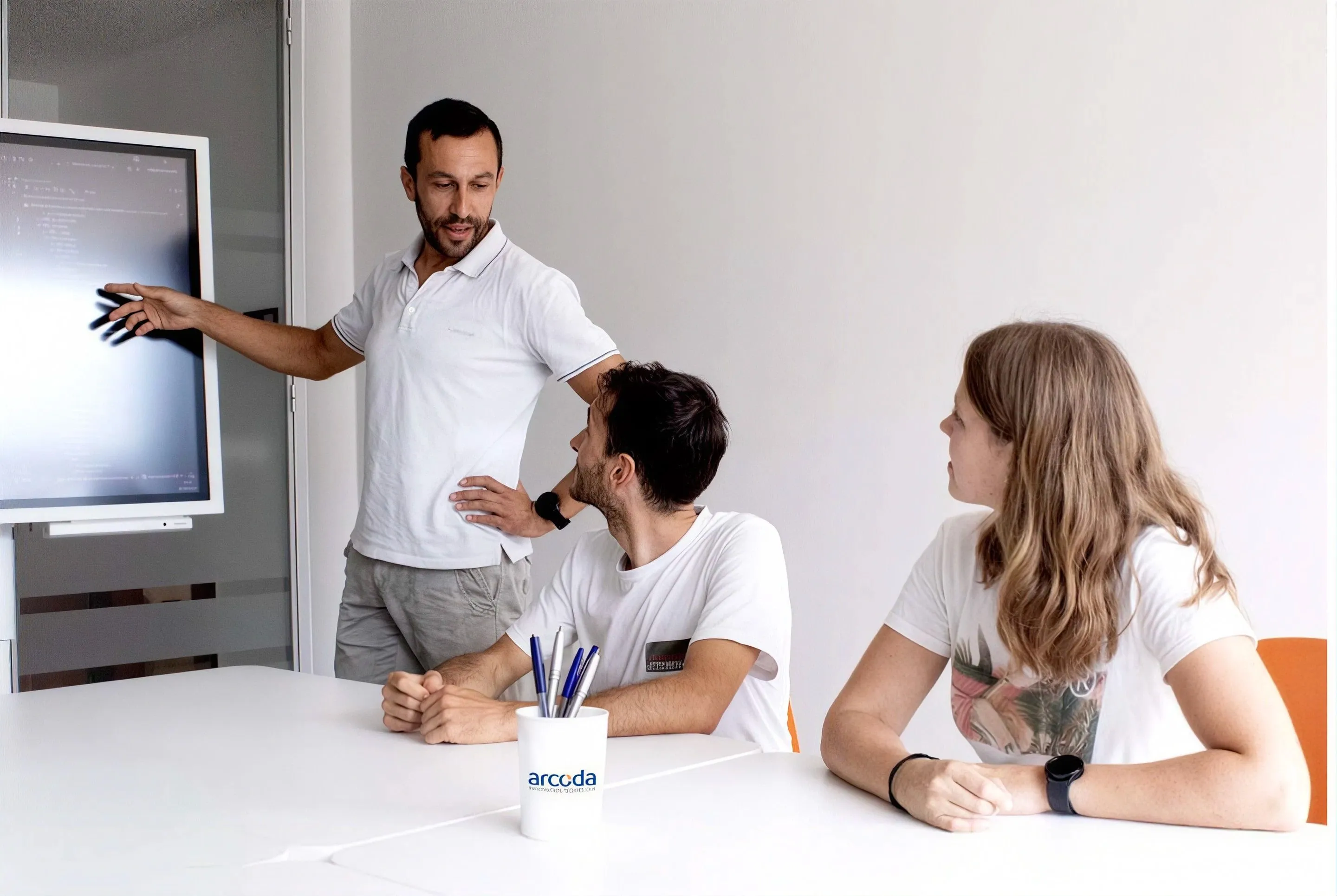 Un collega illustra un progetto sullo schermo a due colleghi seduti al tavolo